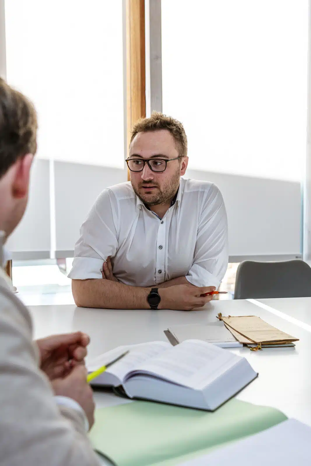 Notaris in gesprek met cliënt over vastgoeddocumenten in modern kantoor van Notariaat Horebeke
