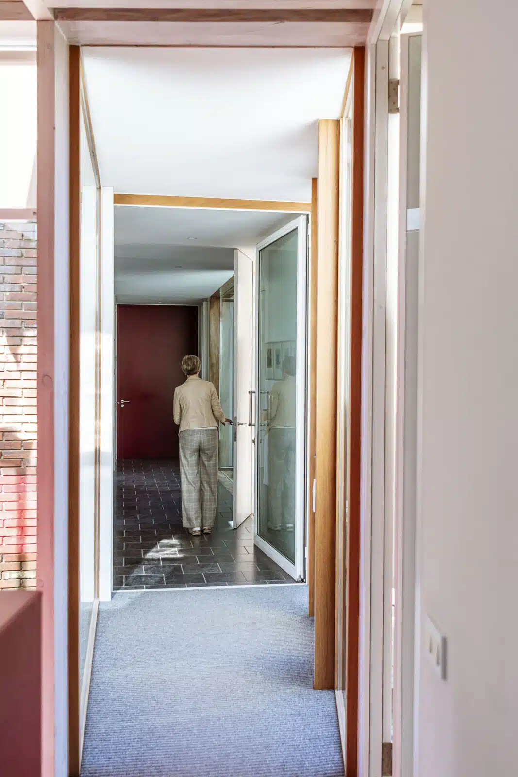 Person walking through modern office hallway with glass doors at Notariaat Horebeke