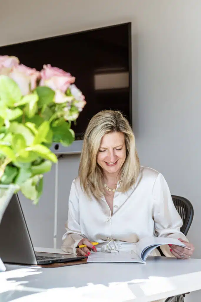 Notaris aan bureau leest document door met laptop en bloemen op kantoor van Notariaat Horebeke