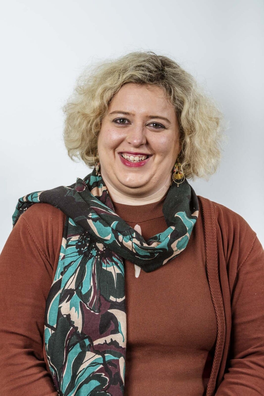 Florence Van der Linden, notarieel jurist bij Notariaat Horebeke, glimlacht in bruine trui met groene sjaal