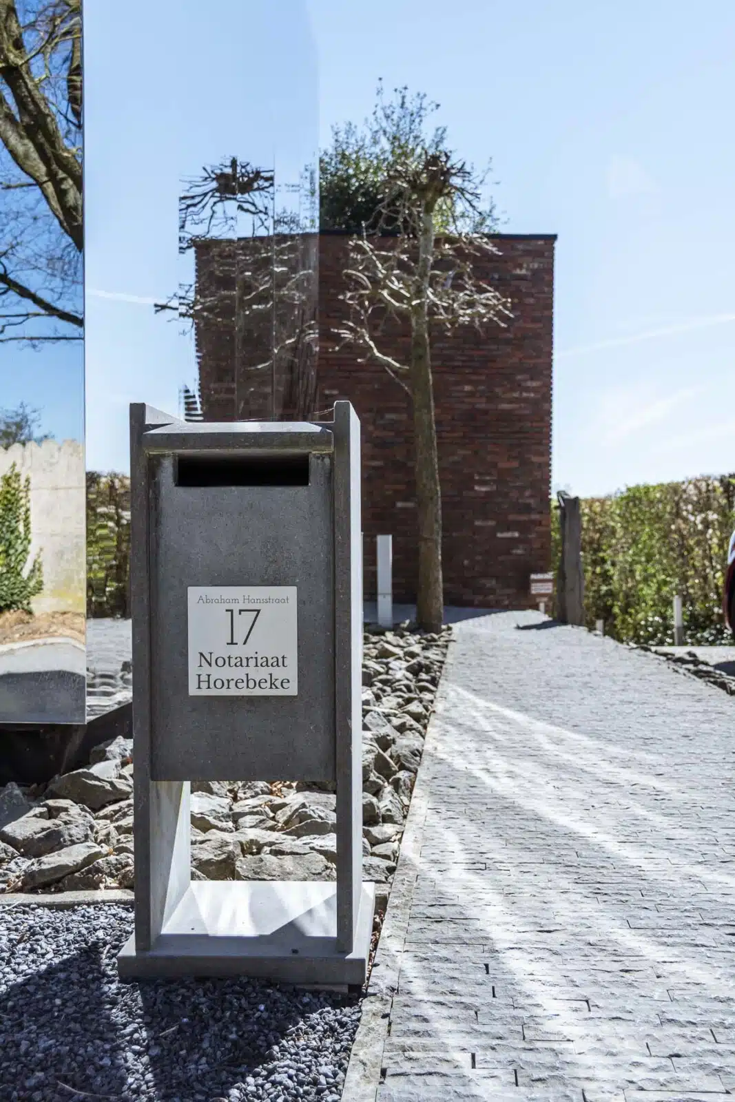 Moderne brievenbus met "17 Notariaat Horebeke" aan Abraham Hansstraat met kasseienpad en bakstenen gebouw